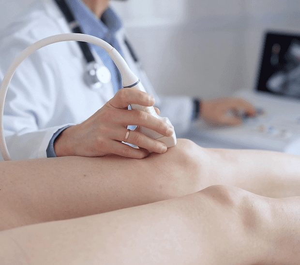 Doctor performing ultrasound on patient's leg.