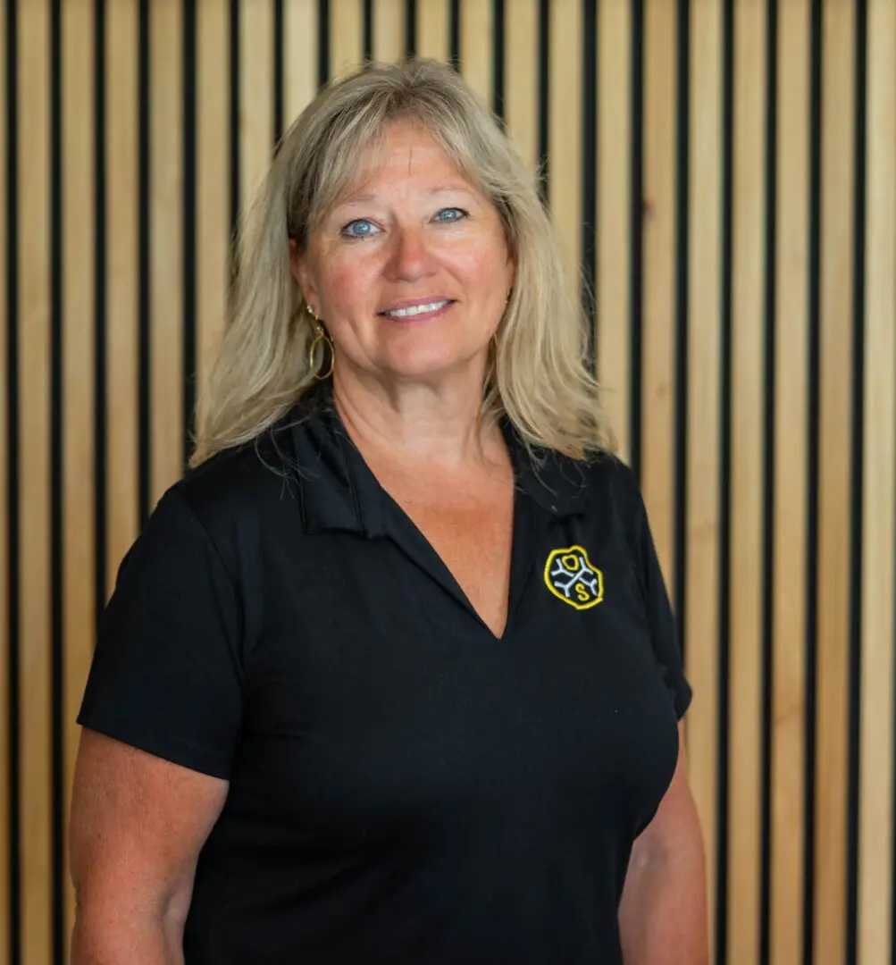 Smiling woman in black polo by wooden slats