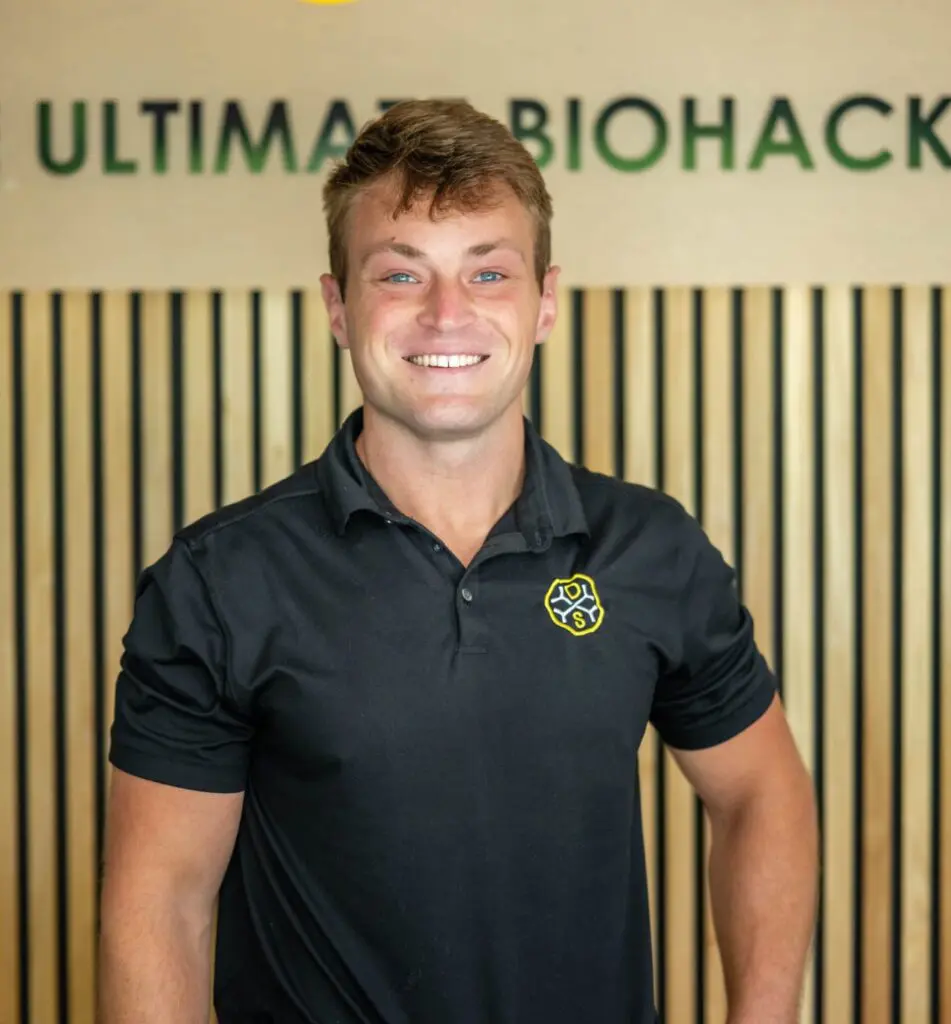 Smiling man in front of wooden wall.